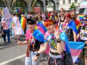 People marching with Pride flags and signs at a parade in Switzerland.