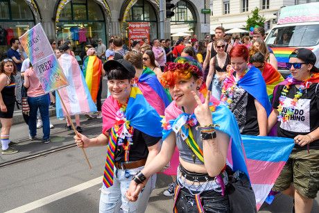 People marching with Pride flags and signs at a parade in Switzerland.
