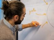 Person writing connected arrows and “goals” on a whiteboard