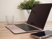 Laptop and smartphone arranged on a tidy wooden workspace with a plant