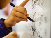 Person pointing at handwritten formulas on a whiteboard